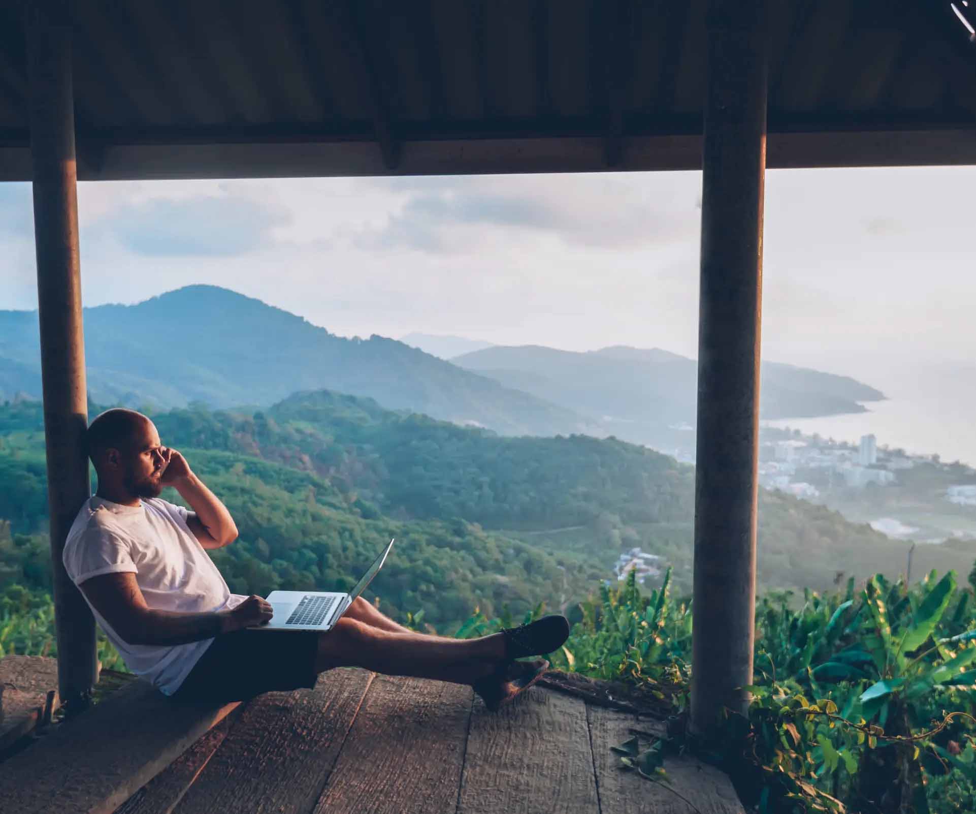 man looking out a view with mobile phone and laptop